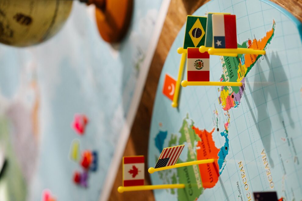 Close-up of North, Central, and South American map with small flags and a globe, highlighting geography and international relations.